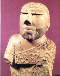 an ancient statue with a beard and moustache on it's face, in front of a purple background