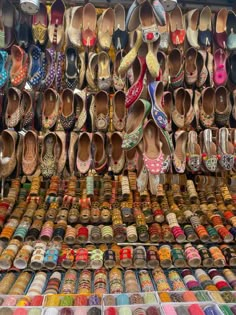 there are many pairs of shoes for sale on the street market stall in india, which is filled with colorfully colored slippers