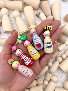 a hand holding several small wooden pegs in it's palm, with different designs on them