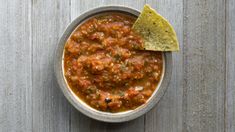 a bowl filled with chili and tortilla chips on top of a wooden table