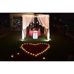 a heart shaped table is set up with lights on the grass for a wedding reception