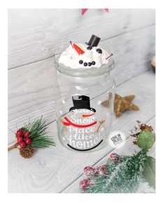 a glass jar filled with whipped cream on top of a white wooden table next to christmas decorations