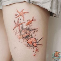 a woman's thigh with tattoos on her legs and starfishs, shells and seaweed