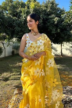 a woman wearing a yellow sari with white flowers on it