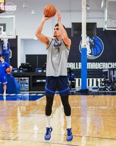 a basketball player is about to dunk the ball in an indoor gym with other players