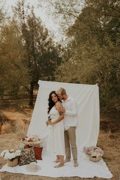 a man and woman standing next to each other on a blanket