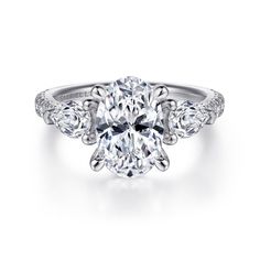 an oval cut engagement ring with three pear shaped diamonds on the band and side stones