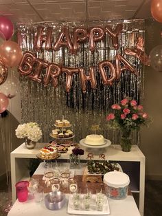 a table topped with lots of cake and desserts next to balloons that say happy birthday