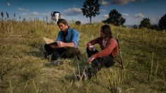 two people sitting on the ground in tall grass