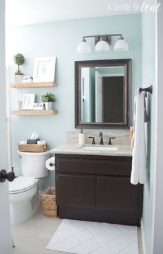 a white toilet sitting next to a sink in a bathroom under a mirror and light blue walls