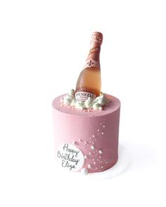 a pink birthday cake with a bottle of champagne on top