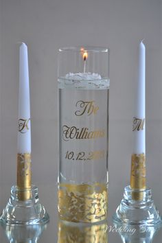 two candles are sitting next to each other in front of a glass with gold foil on it