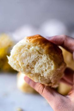 a hand holding a half eaten biscuit in front of the camera, with other pastries behind it