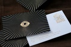 two black and gold business cards with an eye on them are laying next to each other