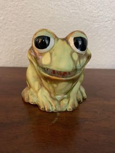 a ceramic frog sitting on top of a wooden table