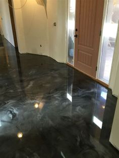 an empty room with black marble floors and pink door on the right side, in front of a white wall