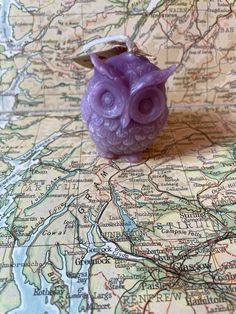 a purple owl figurine sitting on top of a map