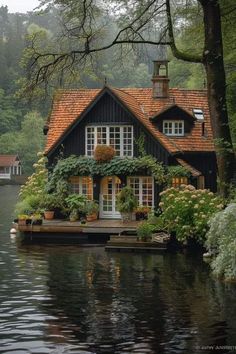 a house sitting on top of a body of water next to lush green trees and bushes