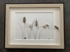 a white frame with some flowers in it on a wall next to a black floor