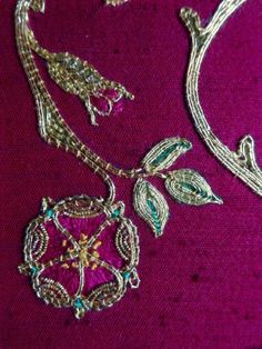 a close up of a piece of jewelry on a purple cloth with gold trimmings