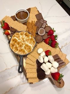 a platter filled with desserts and crackers on top of a white counter