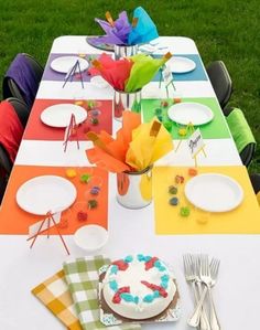 the table is set with colorful paper plates and place settings for an outdoor birthday party