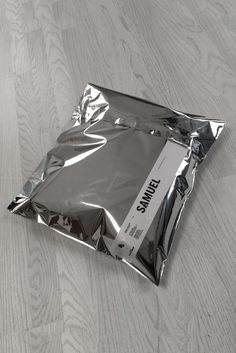 an empty silver bag sitting on top of a wooden floor next to a white wall