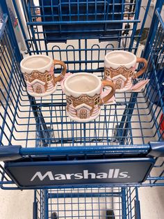 three coffee mugs sitting on top of a blue shopping cart with the words marshmalls