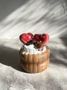 a dessert with strawberries and whipped cream in a vase on a table next to a window