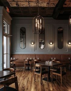 an empty restaurant with wooden tables and chairs in front of the windows, along with mirrors on the wall