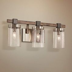 three light bathroom fixture with clear glass and wood accents on the wall in a room