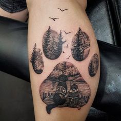 a dog's paw with trees and mountains in the background, on a woman's thigh