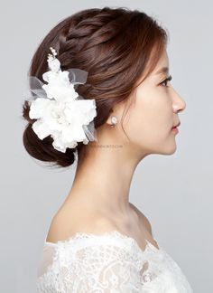 a woman with a flower in her hair wearing a white lace dress and pearl earrings