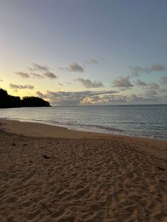 an empty beach at sunset with the ocean in the background