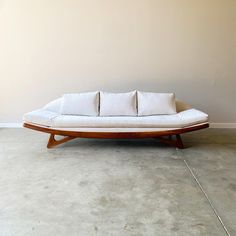 a white couch sitting on top of a cement floor next to a wooden frame wall