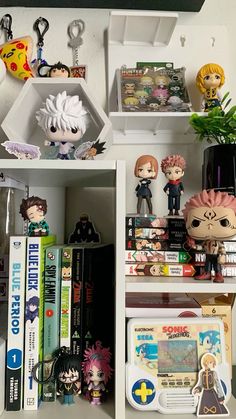 some anime figurines and books on a shelf in a room with white walls