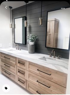 a bathroom with two sinks and mirrors on the wall, along with wooden cabinetry