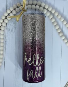 a purple and silver glitter tumbler with the words hello fab on it next to beads