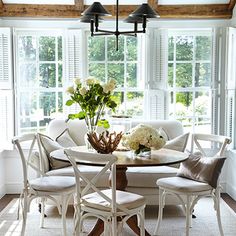 a dining room table with four chairs and a bench in front of the bay window