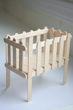 a wooden toy crib sitting on top of a white floor next to a window