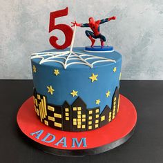 a birthday cake with a spiderman figure on top and the number 5 in the middle