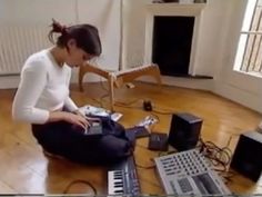 a woman sitting on the floor in front of a laptop and other electronic equipment,