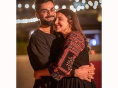 a man and woman hugging each other in front of lights