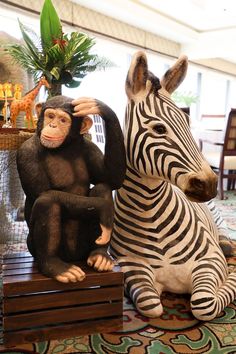 there are two statues of monkeys and a zebra sitting on the floor next to each other