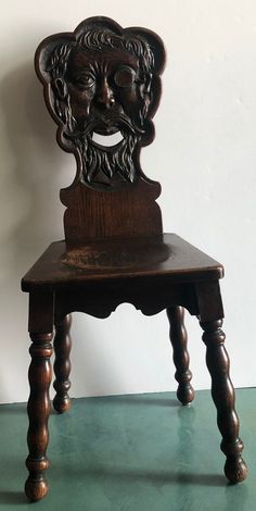 an old wooden chair with a carved face on it