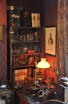 an old fashioned desk with lots of clutter on it and a lamp in the corner