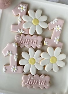 decorated cookies are arranged in the shape of numbers and daisies on a white platter