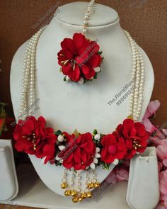 a necklace and earring set with red flowers on display next to other jewelry items