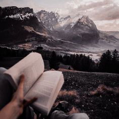 someone is reading a book in the mountains