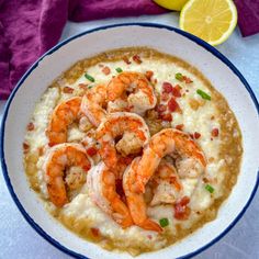 a bowl of shrimp and gritee with a lemon slice next to it on a table